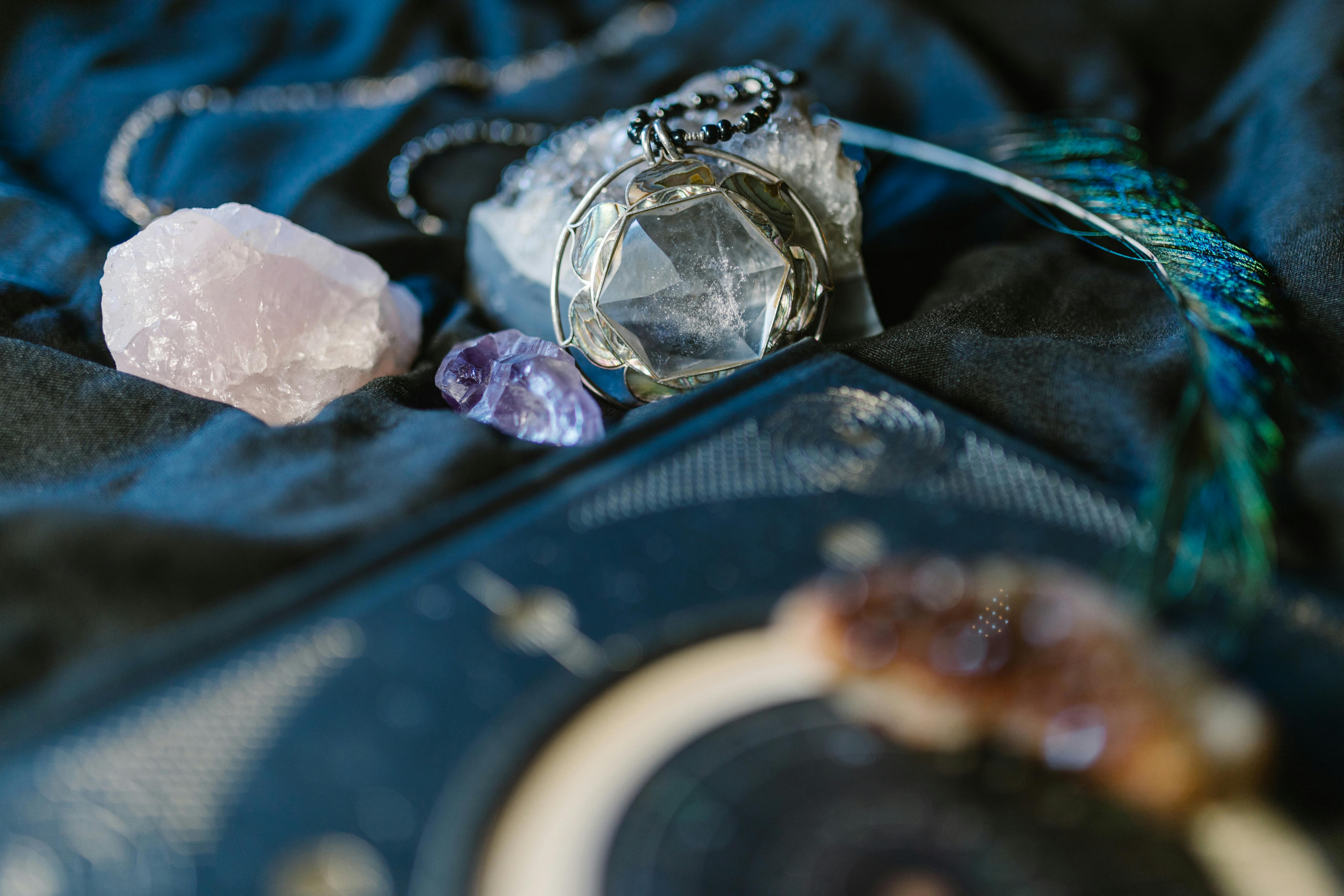 Crystal pendulum and raw stones on blue velvet